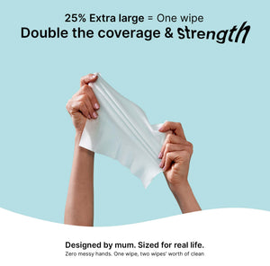 Hands holding an extra-large Travel baby wipe, showcasing its strength and coverage.