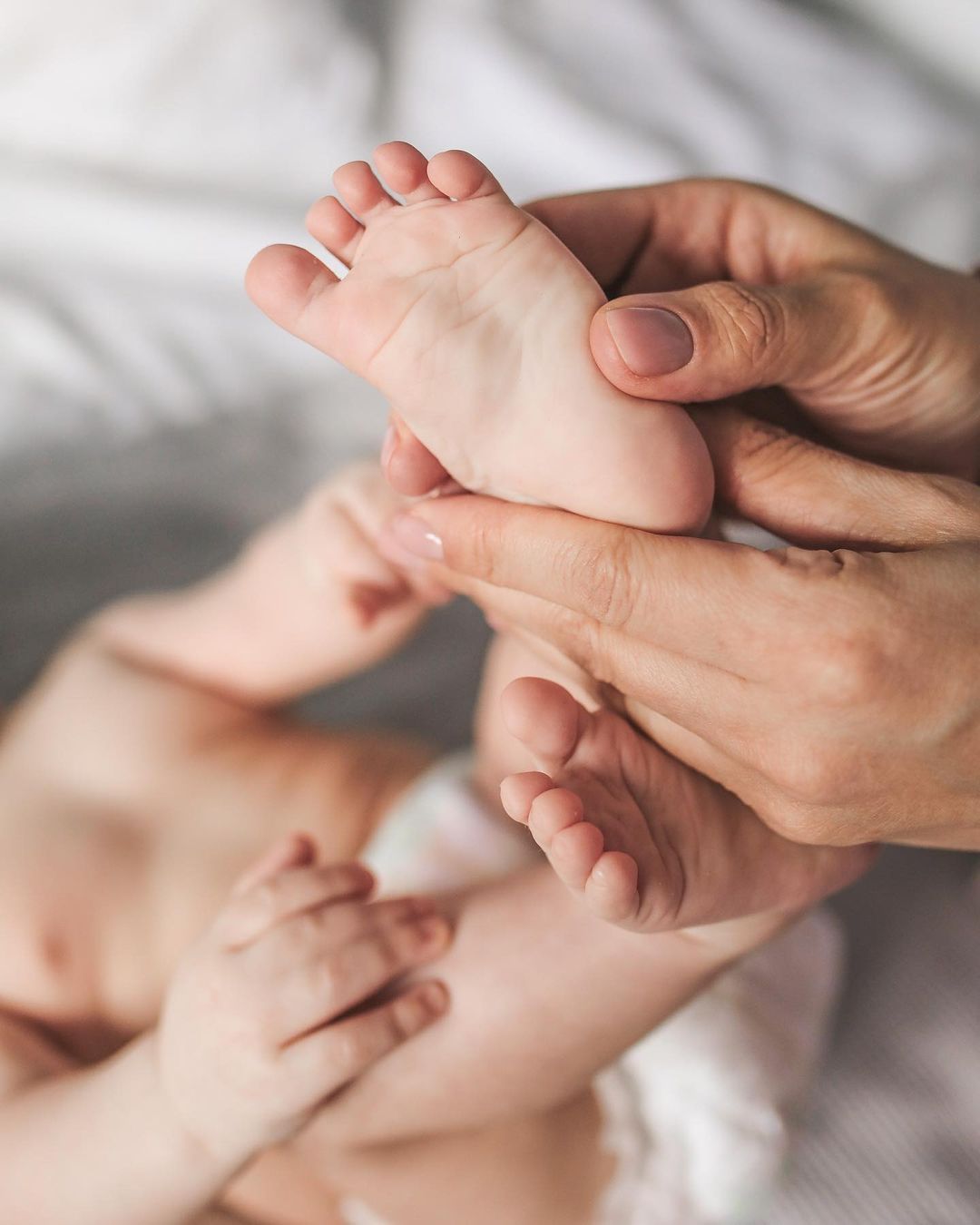 Close-up of baby's feet gently held by mom